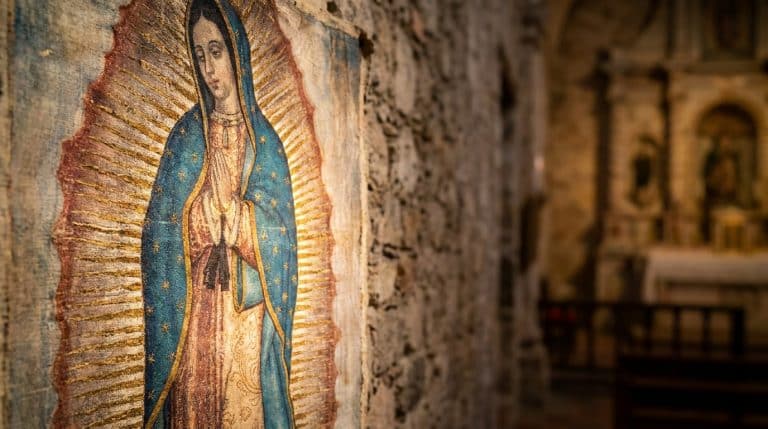 Représentation de Notre-Dame de Guadalupe sur un mur de pierre dans une église floue.